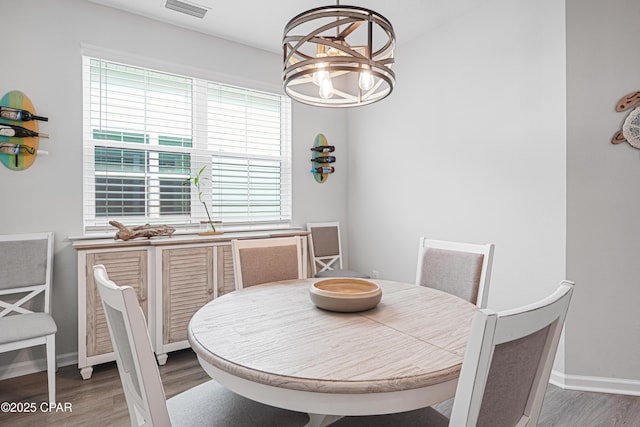 dining space with baseboards, visible vents, wood finished floors, and a notable chandelier