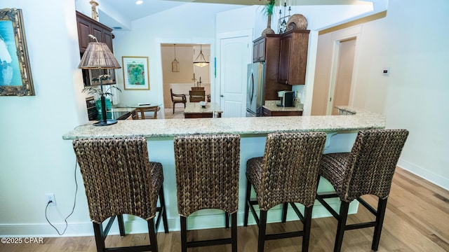 kitchen with freestanding refrigerator, dark brown cabinets, baseboards, and light wood finished floors