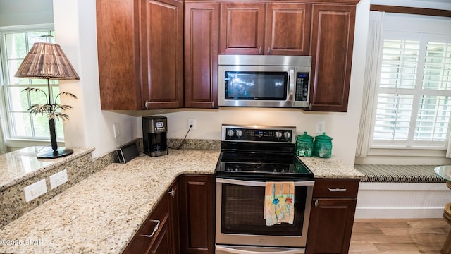 kitchen with light stone counters, light wood finished floors, and stainless steel appliances