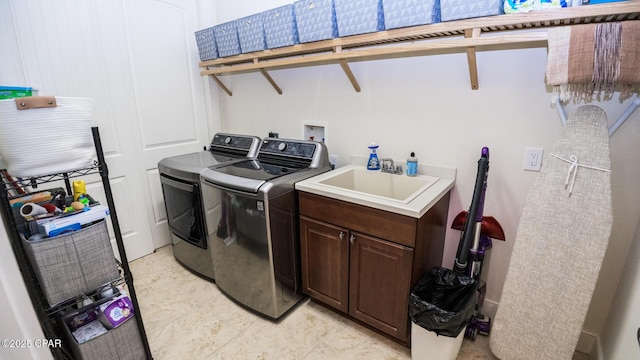 clothes washing area featuring a sink, cabinet space, and washing machine and clothes dryer