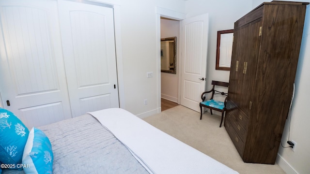 bedroom featuring baseboards, light colored carpet, and a closet