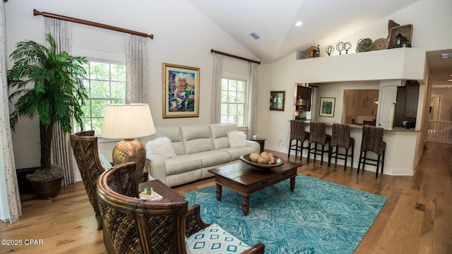 living room featuring visible vents, wood finished floors, and lofted ceiling