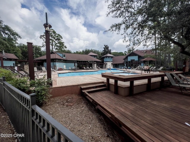 community pool featuring fence and a wooden deck