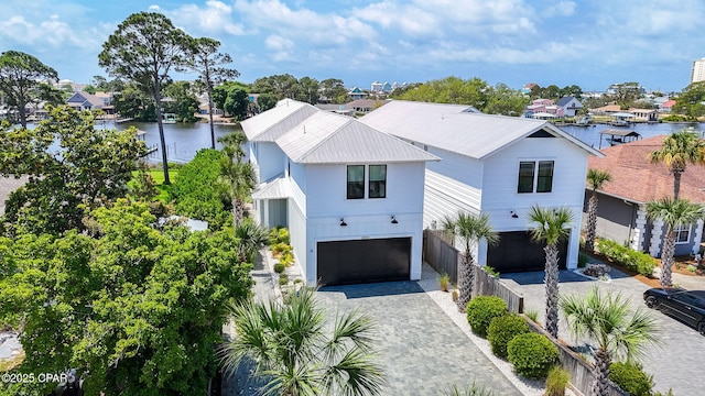 8597 N Lagoon Dr, Panama City, FL 32408 - view of front of home featuring a water view, a residential view, a garage, metal roof, and decorative driveway
