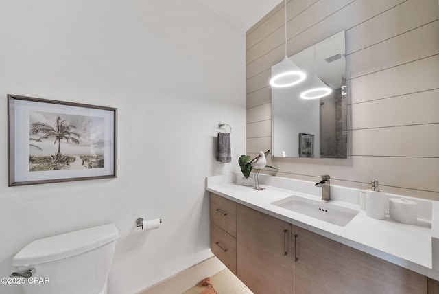 8597 N Lagoon Dr, Panama City, FL 32408 - bathroom with toilet, wood walls, and vanity
