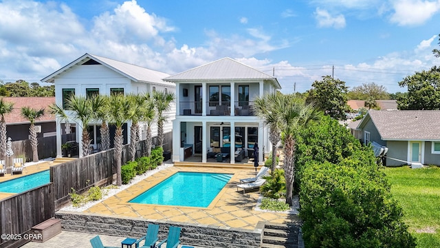 8597 N Lagoon Dr, Panama City, FL 32408 - back of property with a balcony, a fenced in pool, metal roof, a patio area, and a fenced backyard
