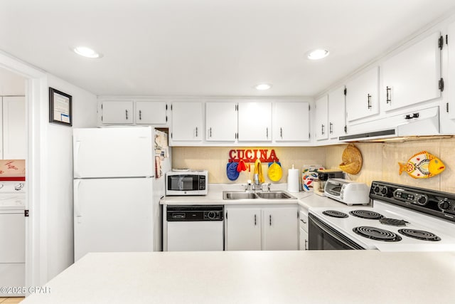 kitchen featuring washer / dryer, white appliances, light countertops, under cabinet range hood, and a sink