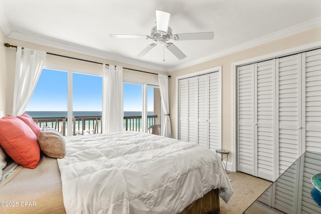 carpeted bedroom with crown molding, multiple closets, access to exterior, a ceiling fan, and a water view