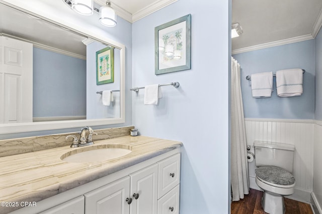 bathroom with wood finished floors, a wainscoted wall, vanity, toilet, and ornamental molding