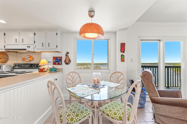 dining space featuring baseboards, ornamental molding, a toaster, and light tile patterned flooring