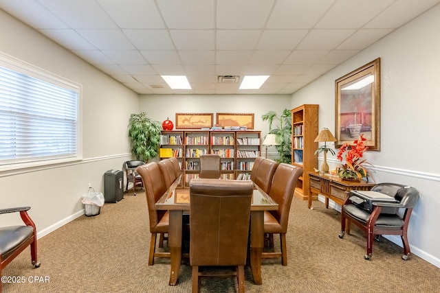 carpeted dining room with a drop ceiling and baseboards