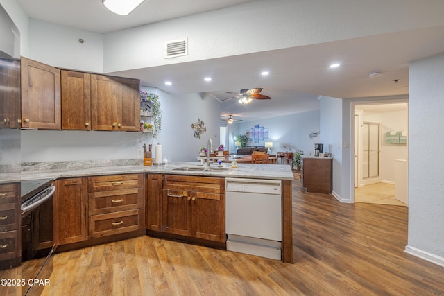 kitchen featuring white dishwasher, range with electric stovetop, a peninsula, a sink, and light wood-type flooring