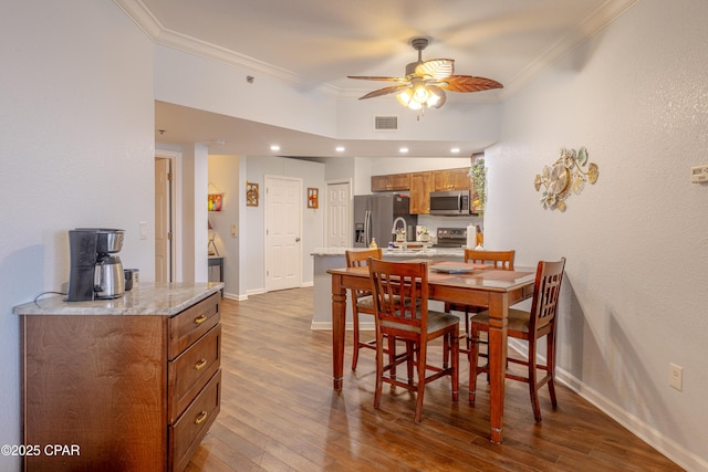 dining space with a ceiling fan, crown molding, dark wood-type flooring, and baseboards