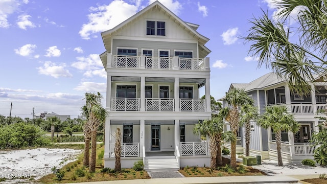 raised beach house with board and batten siding, a porch, and a balcony