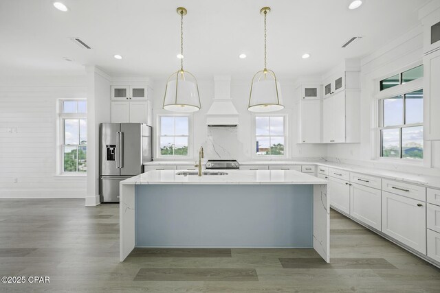 kitchen with a sink, plenty of natural light, stainless steel appliances, and custom range hood