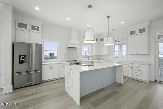 kitchen with crown molding, a sink, light wood finished floors, stainless steel appliances, and custom range hood
