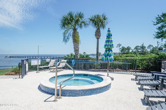 view of pool featuring a hot tub, a water view, and fence