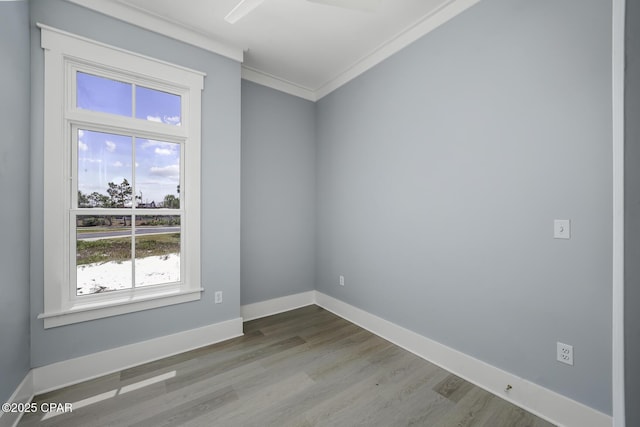 empty room with baseboards, ornamental molding, and wood finished floors