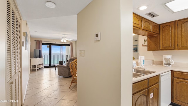 kitchen featuring visible vents, white dishwasher, brown cabinets, light countertops, and open floor plan