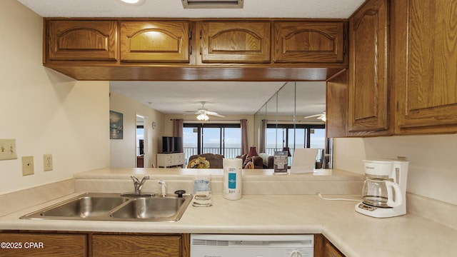 kitchen with brown cabinetry, a sink, a ceiling fan, and dishwasher