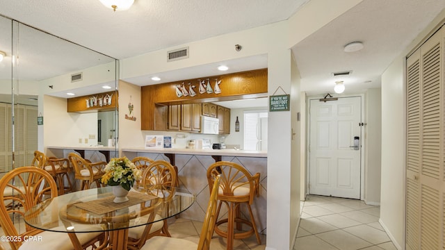 dining room featuring a textured ceiling, visible vents, and light tile patterned floors