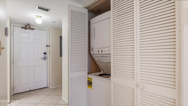 laundry room with stacked washer / drying machine, laundry area, a textured ceiling, light tile patterned floors, and visible vents