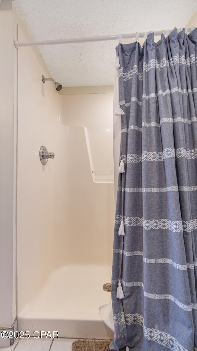 bathroom with a textured ceiling and a stall shower