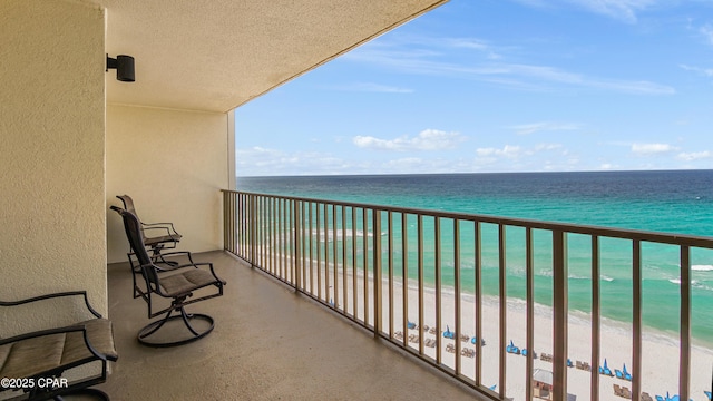 balcony with a water view and a view of the beach
