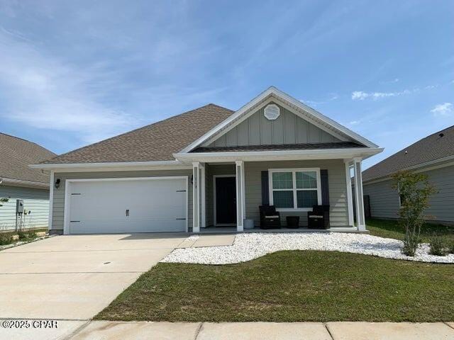 ranch-style house featuring an attached garage, a front lawn, board and batten siding, concrete driveway, and covered porch