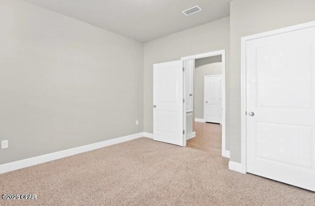 unfurnished bedroom with baseboards, light colored carpet, and visible vents