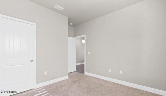 unfurnished bedroom with baseboards, light colored carpet, and visible vents