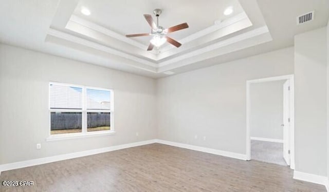 empty room with ceiling fan, a raised ceiling, recessed lighting, wood finished floors, and visible vents