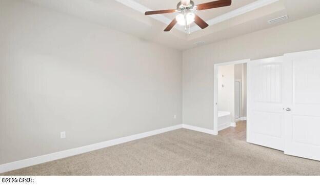 interior space with baseboards, a raised ceiling, carpet, and a ceiling fan