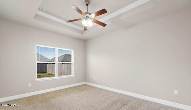 spare room featuring carpet flooring, baseboards, ceiling fan, and a raised ceiling