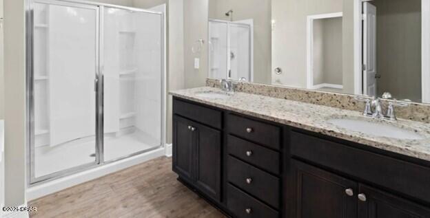 full bathroom with a sink, a shower stall, and wood finished floors