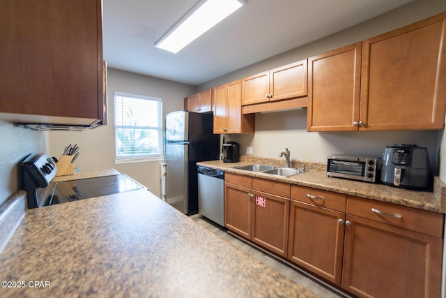 kitchen with a sink, stainless steel appliances, light countertops, and brown cabinetry