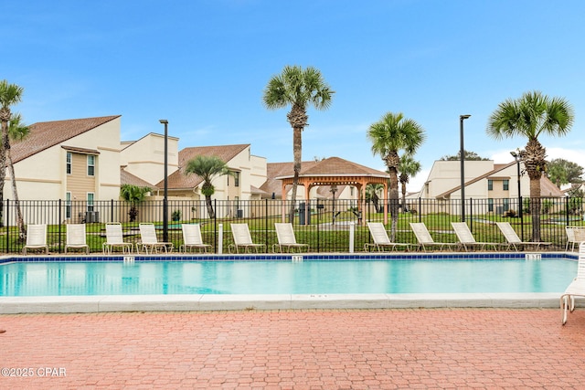 community pool with fence, a gazebo, and a residential view