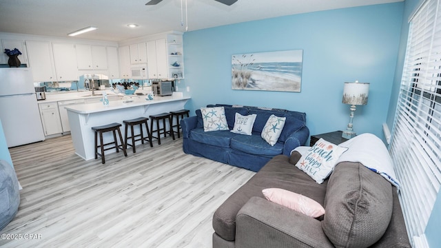 living room with light wood-style flooring and ceiling fan