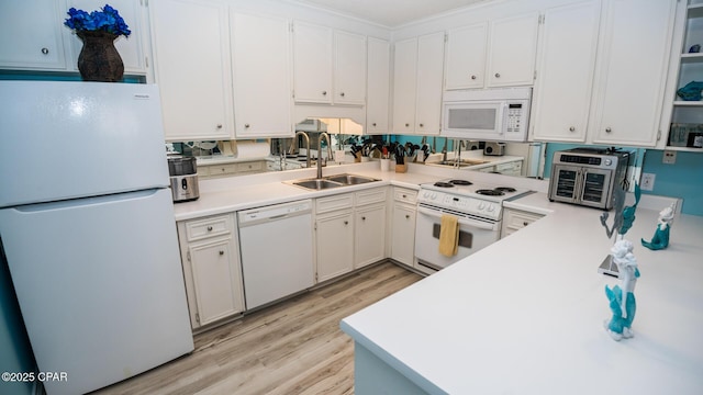 kitchen with white cabinets, a sink, light wood finished floors, white appliances, and light countertops