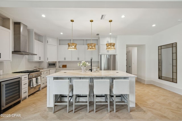 kitchen featuring wall chimney range hood, a kitchen breakfast bar, visible vents, beverage cooler, and stainless steel appliances
