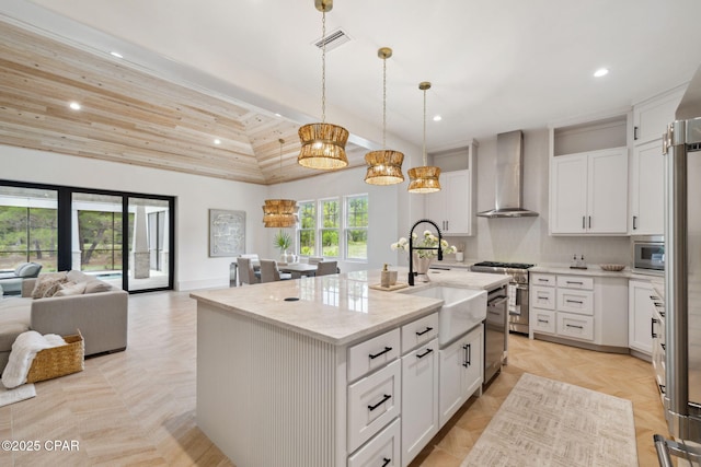kitchen featuring appliances with stainless steel finishes, white cabinetry, a sink, recessed lighting, and wall chimney exhaust hood