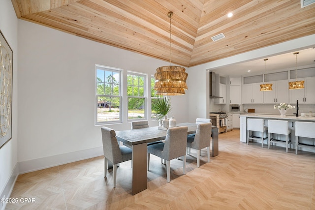 dining area featuring visible vents, baseboards, a high ceiling, and wood ceiling