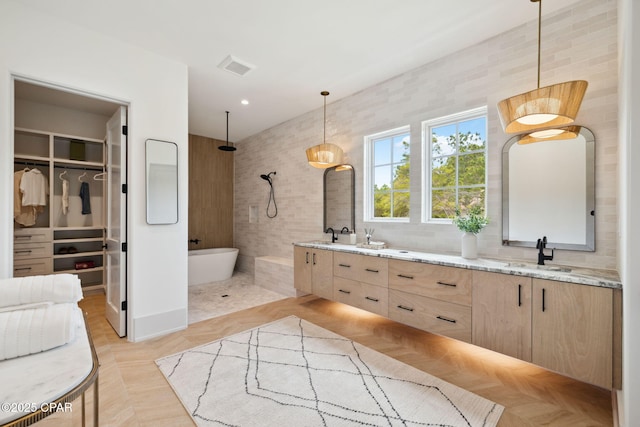 full bath featuring double vanity, walk in shower, a sink, a spacious closet, and a soaking tub