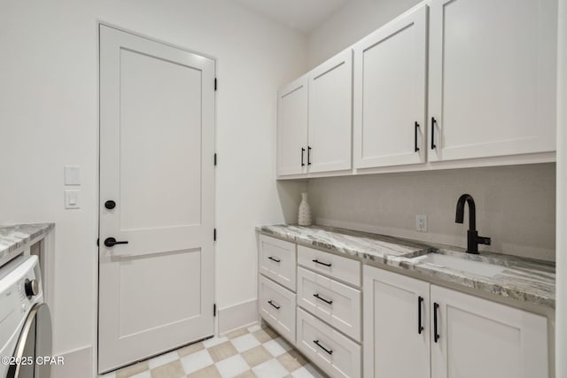 laundry area with cabinet space, washer / clothes dryer, a sink, and light floors