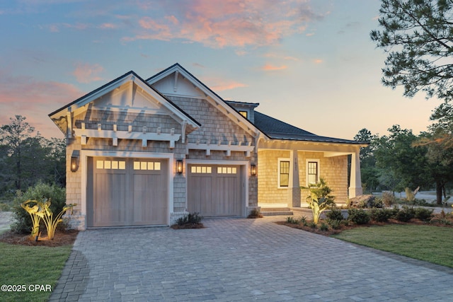 craftsman-style home featuring covered porch, an attached garage, a yard, and decorative driveway