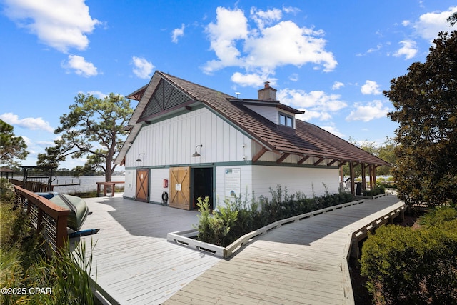 exterior space featuring board and batten siding, a wooden deck, and a chimney