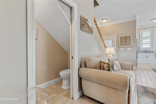 interior space with toilet, baseboards, wood finish floors, vanity, and ornamental molding