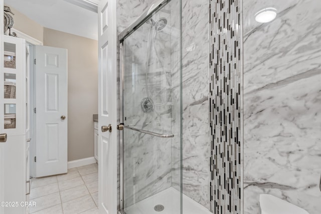 full bathroom featuring a marble finish shower, baseboards, and tile patterned floors