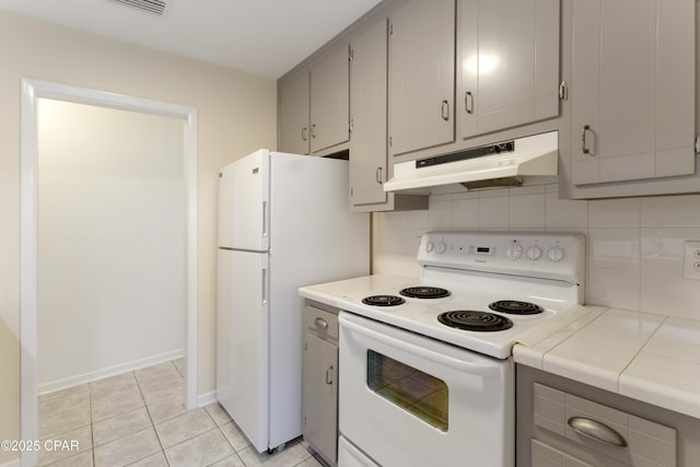 3947 Verona Cir, Panama City, FL 32405 - kitchen with white appliances, gray cabinetry, under cabinet range hood, and tile countertops
