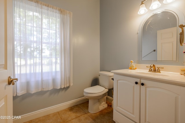 half bathroom featuring tile patterned floors, baseboards, vanity, and toilet